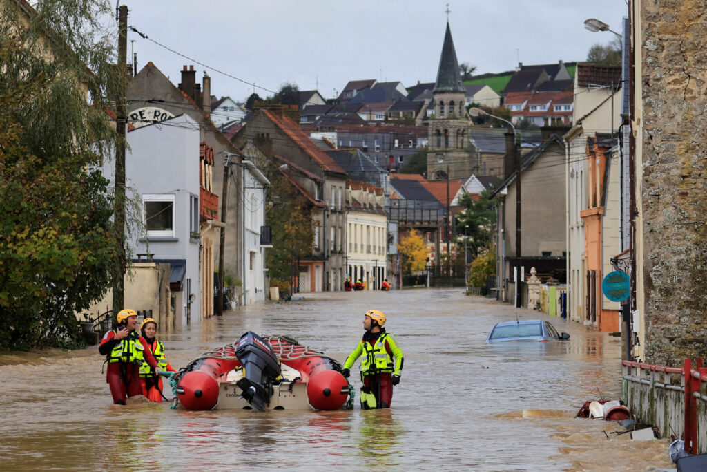 French firefighters walk on a flooded street to evacuate residents by boat as the La Liane River overflows in Saint-Etienne-au-Mont, near Boulogne-sur-Mer after heavy rain causing flooding in northern France, November 7, 2023.