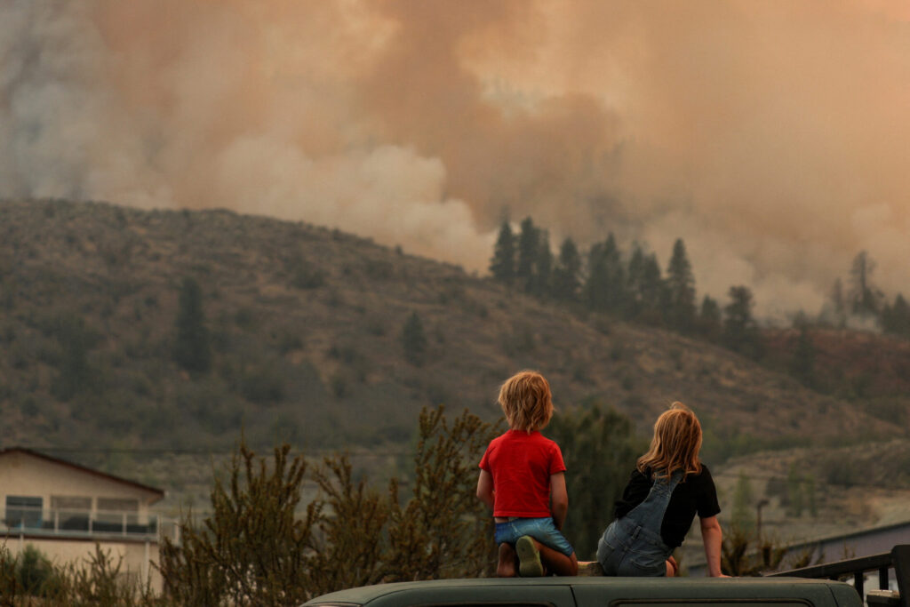 FILE PHOTO: Locals gather to watch firefighting efforts amid heavy smoke from the Eagle Bluff wildfire, after it crossed the Canada-U.S. border from the state of Washington and prompted evacuation orders, in Osoyoos, British Columbia, Canada July 30, 2023.